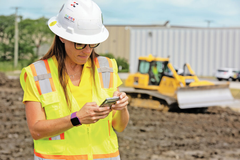 A construction worker uses her phone in front of a Komatsu dozer