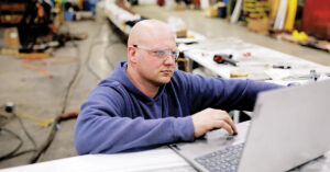 Heavy equipment training simulators: Man using a laptop in a workshop