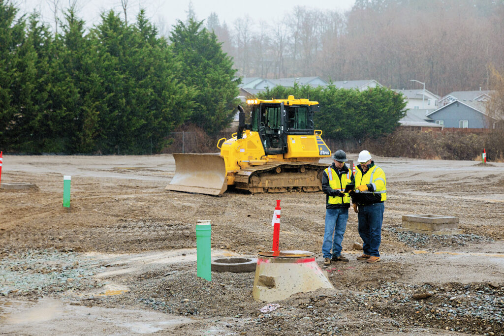 Two construction workers discussing plans in front of a D51PXi Dozer