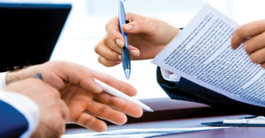 Lien Rights - Waive your right to a lien - Two sets of hands with pens looking over papers