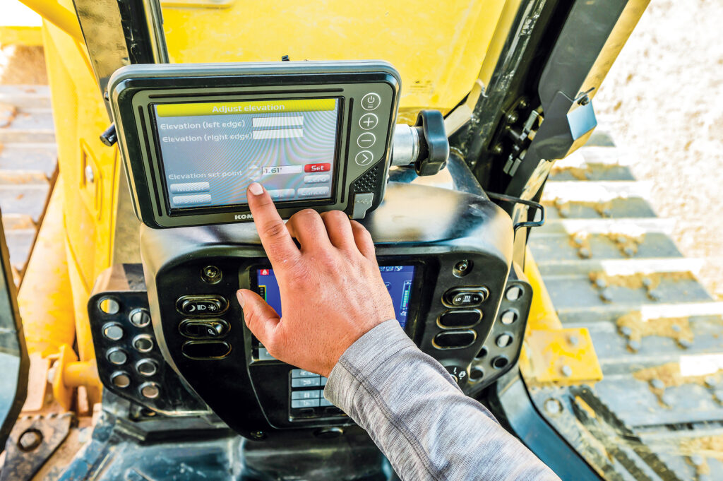 A person using the display on a Komatsu D71EXi dozer to set the elevation set point