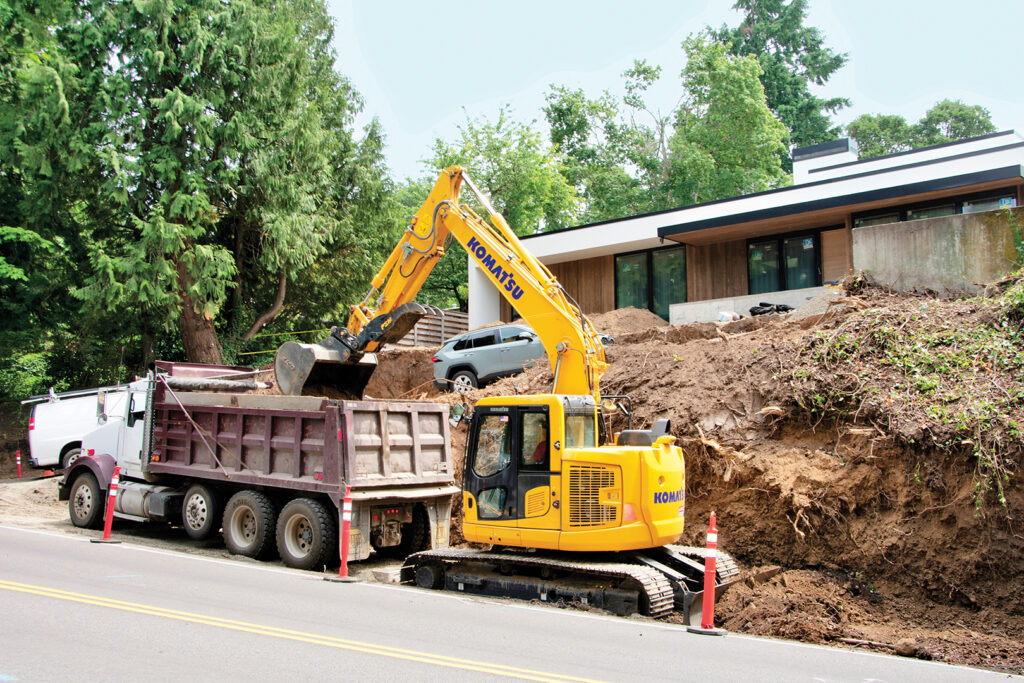 A Komatsu tight tail swing excavator loads a truck in a residential area