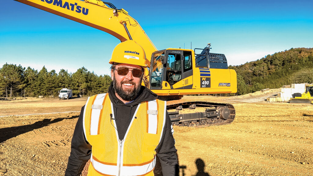 An image of Nathaniel Waldschmidt, Product Manager, Komatsu standing in front of a Komatsu PC490LCi Excavator