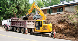 A Komatsu tight tail swing excavator loads a truck in a residential area