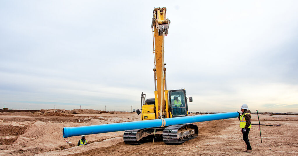 A Komatsu excavator holding up a pipe | Bipartisan Infrastructure Law