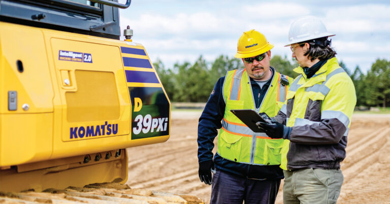 An image of certified technicians looking at a tablet in front of a Komatsu D39PXi dozer