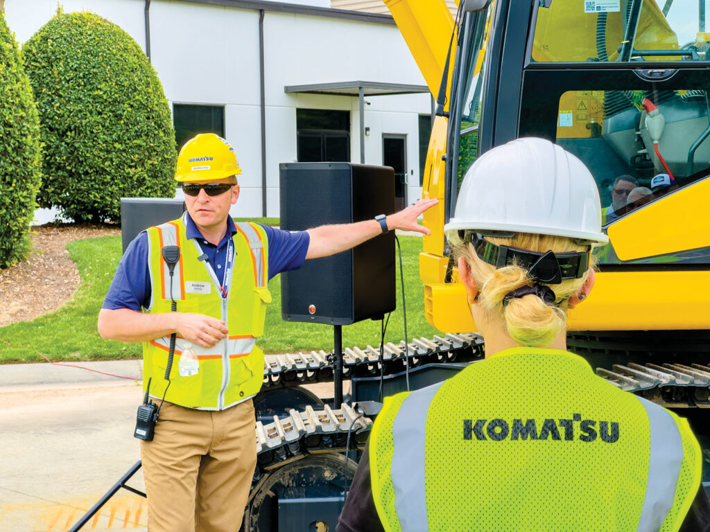 Andrew Earing speaking to customers in front of a Komatsu PC210LCE electric excavator