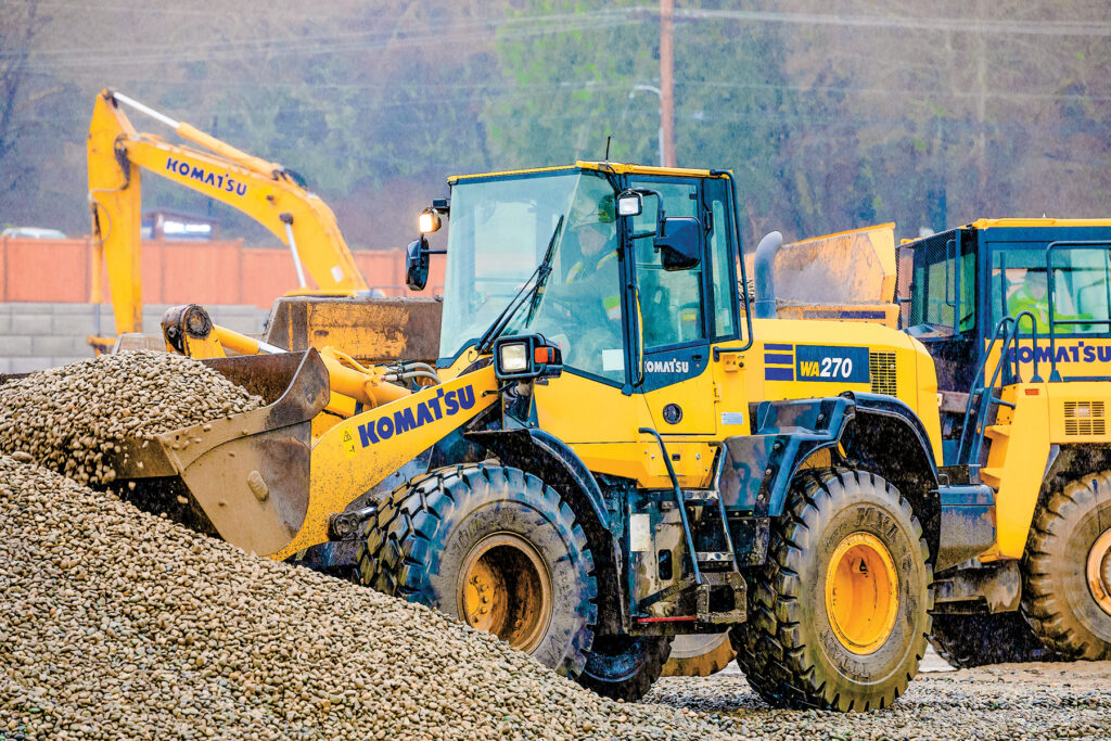 A Komatsu WA270 wheel loader moving rocks at a job site