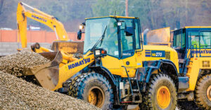 A Sourcewell provider | A Komatsu WA270 wheel loader moving rocks at a job site