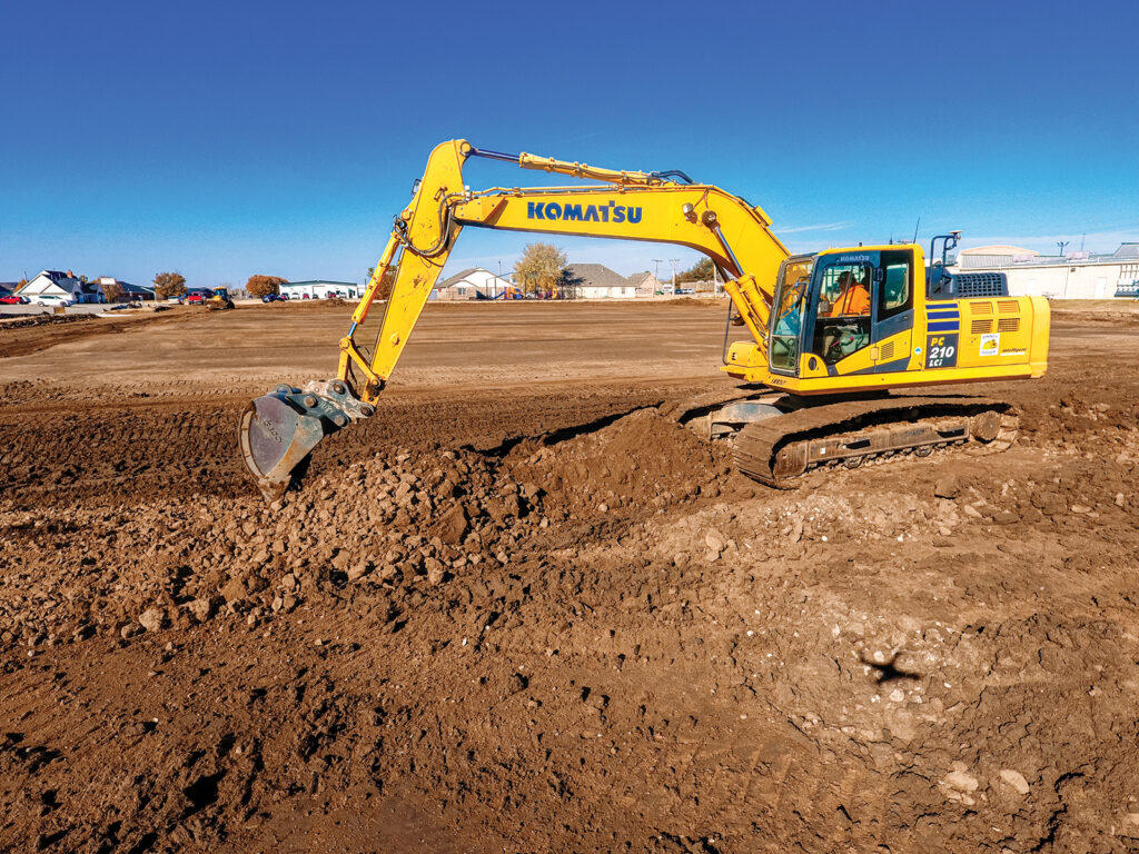 A Komatsu PC210LCi excavator moves dirt