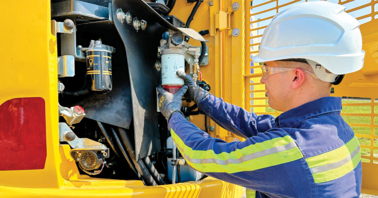 A technician works on a Komatsu machine showcasing the importance of technicians in the heavy equipment industry in alignment with AEDF’s Vision 2025 initiative