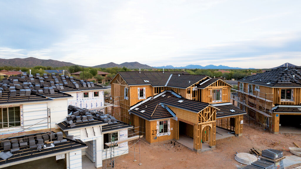 An image of three houses under construction with mountains in the background